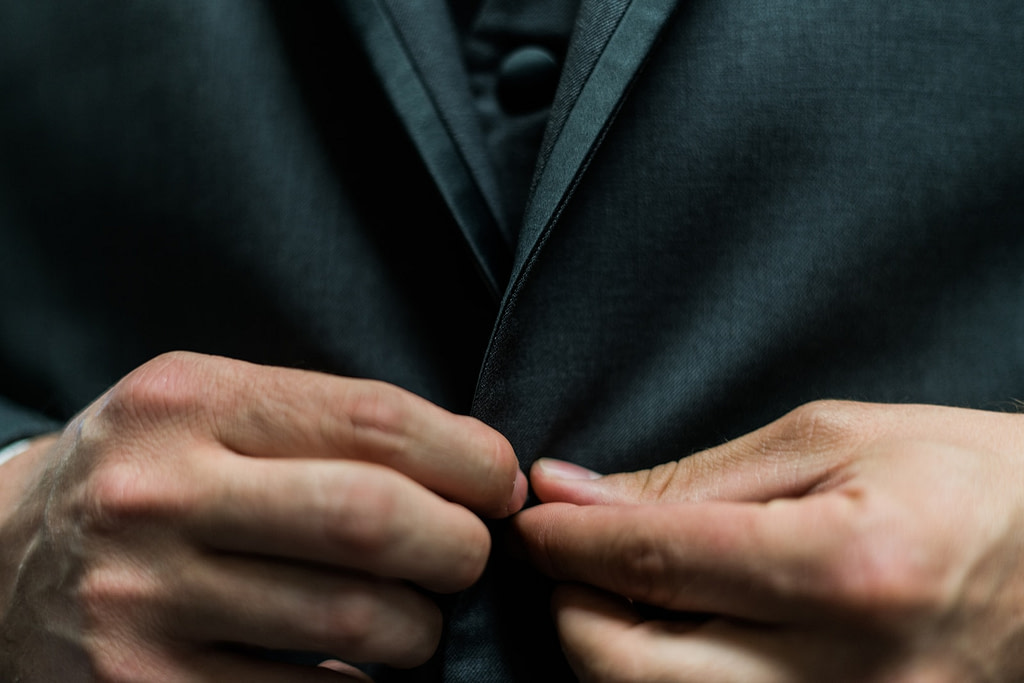 person holding black suit jacket button